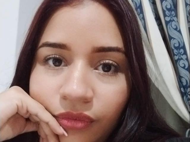 Altair has a shiny, tan-skinned face with dark brown eyes, straight black hair, and pink lips, resting her hand on her cheek in a selfie.