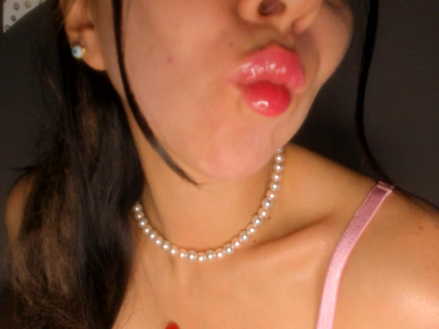 FairyBeauti's pouty pink lips are glossy, with a pearl necklace and pink strap, dark hair partially visible, wearing a diamond earring on her left ear.