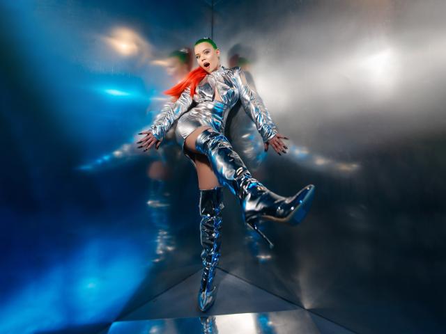EnergyBurnny in shiny silver metallic outfit, green mohawk, red scarf, and knee-high silver boots, mid-air, mouth open, reflecting on a reflective surface, blue and white lighting.