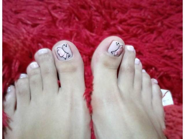 ErotiicAlexa's toes have cute, small black bird drawings on pale pink nail polish. Her toes are on a bright red, fluffy surface. Boobs are not visible.