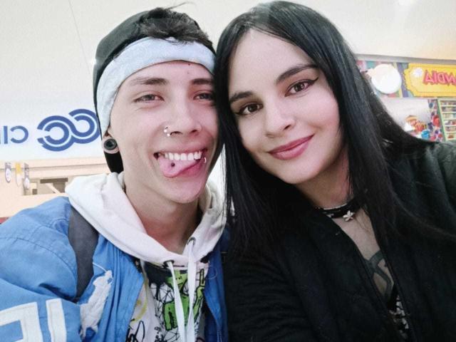 PuccaGaru69 with black hair, nose ring, and choker, next to PuccaGaru69 with headband, blue jacket, white hoodie, and tongue out. Both smiling. PuccaGaru69 on right.