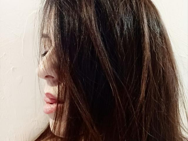 AliceSunset's face with long, messy brown hair covering her eyes, showing her pink lips slightly parted. Her skin is light, and she's looking to the side.