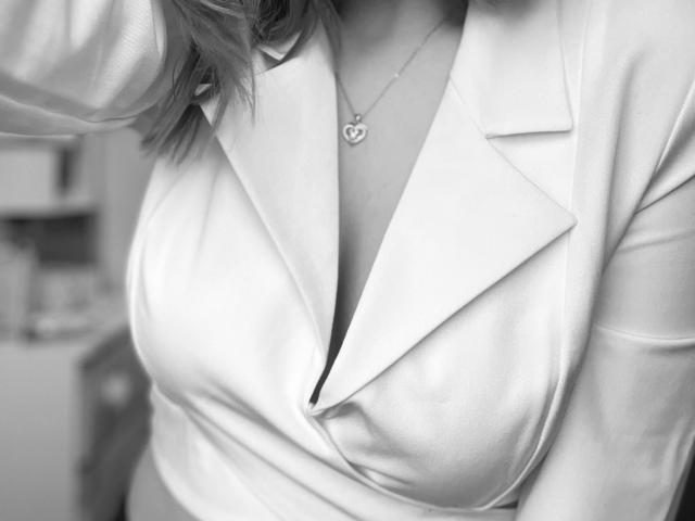 Scarlet-Young-hot wearing a white, button-up blouse with a deep V-neck, showing her big, soft, round tits, and a heart-shaped necklace. Black-and-white, slightly blurred.