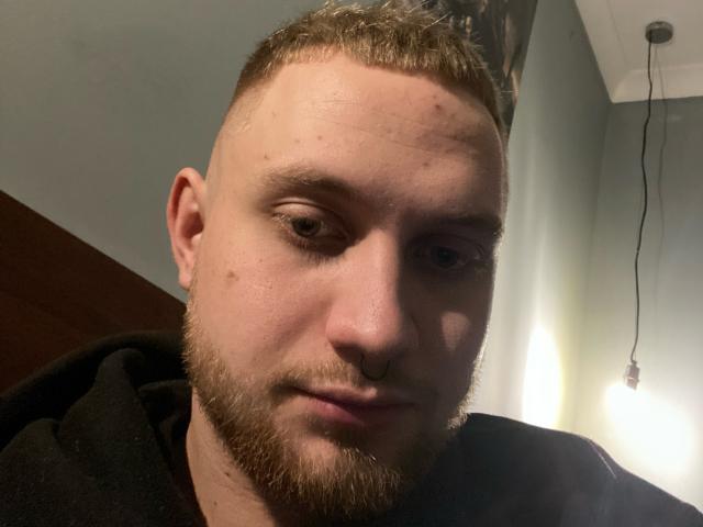 VityaKabura's face, showing a bald head with a short, trimmed beard and nose ring, wearing a black hoodie, with a slightly curious and relaxed expression.