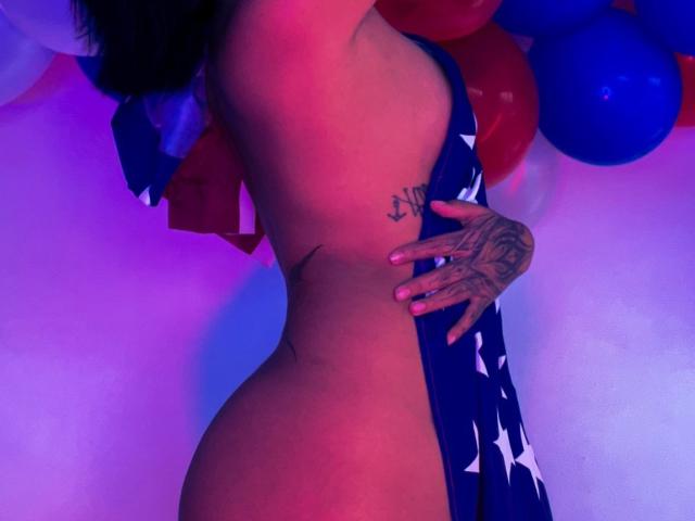 JuliaRoseKs, naakt, profiel van de zijkant, houdt de Amerikaanse vlag vast, tatoeage op de ribben, hand met tatoeage, roze-blauwe belichting, rode-blauwe-witte ballonnen, rond, bil, borsten, donker haar, zichtbare tepel..