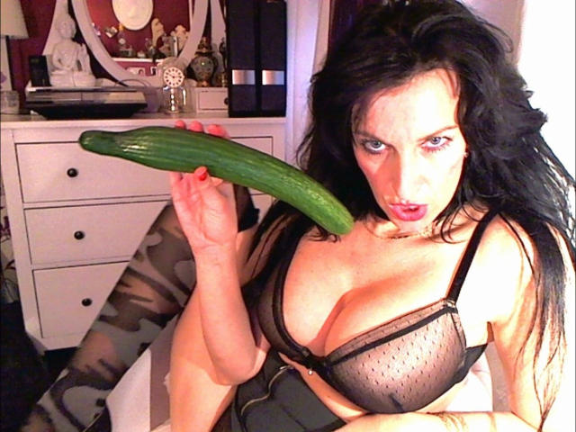 Lady4youLive-hot with big tits, black bra, holding a huge cucumber near her mouth, looking surprised. She's got long black hair and a sexy, seductive expression.