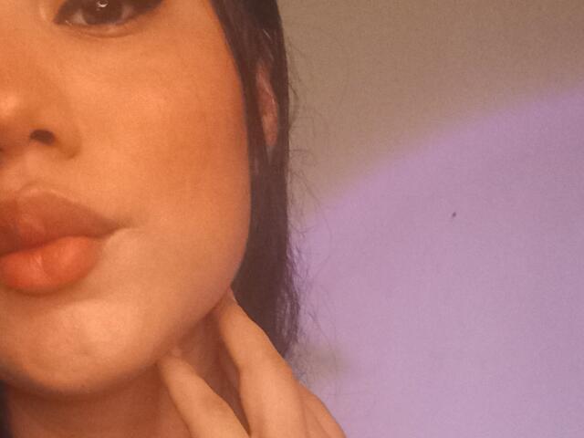 SteffanyTaylor's pouty ass-kissing lips, slightly parted, with her hand gently touching her neck. She has dark hair, a nose piercing, and warm skin. Her finger is visible.