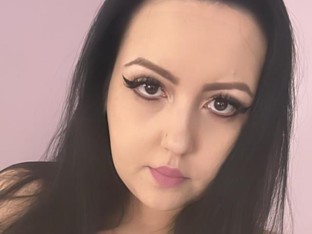 LuizaDavis has long black hair, thick eyelashes, and pink lipstick. Her brown eyes are slightly upturned, and she has a small nose piercing. Her ass is not visible.