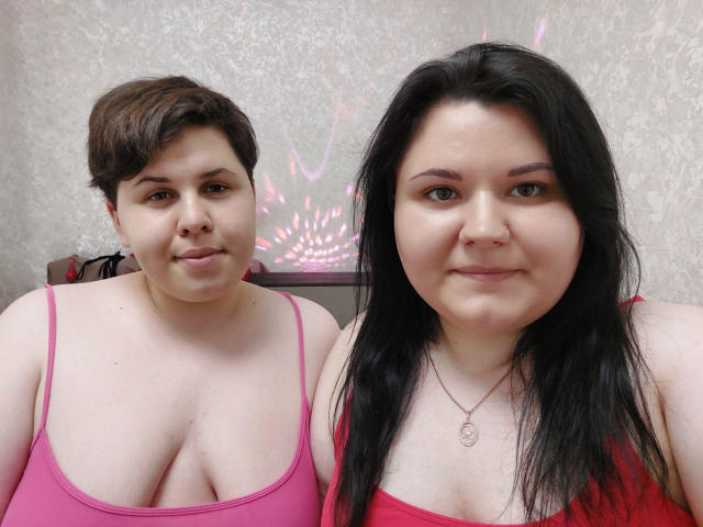 BeckyAndEllen with short brown hair and small tits in a pink top, and BeckyAndEllen with long black hair and small tits in a red top, smiling.