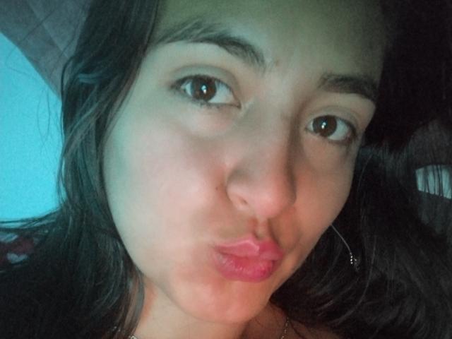 VenusSweetPalmer with pouty pink lips, brown eyes, and dark wavy hair, looking into the camera with a slight smirk. Her face is centered, with a subtle light shadow.