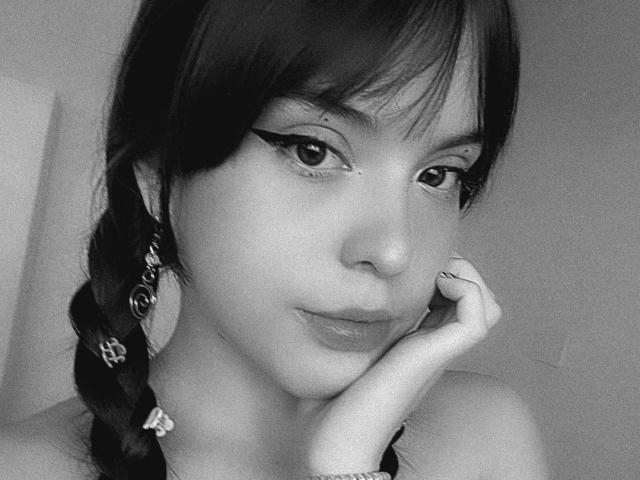 Black-and-white selfie of SpaceValentine with dark braided hair, winged eyeliner, and pouty lips, resting her chin on her hand, showing a ring on her finger.