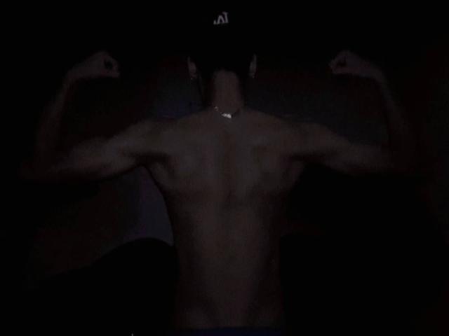 Fraxel is shirtless, flexing both arms with muscular back and chest visible, wearing a dark cap, and has a necklace. Fraxel's ass is not visible.