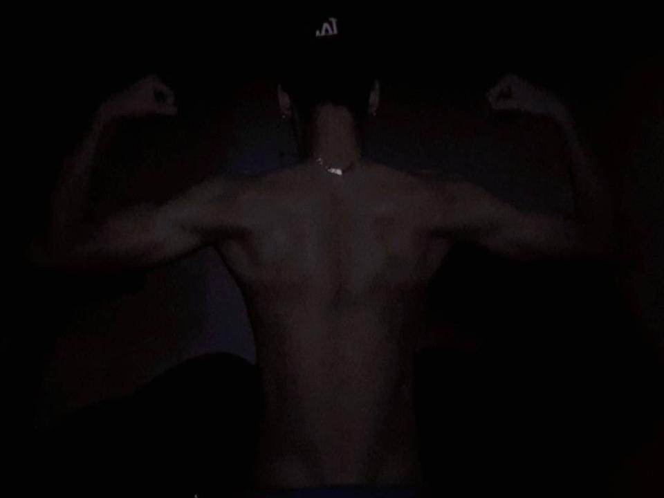 Fraxel is shirtless, flexing both arms with muscular back and chest visible, wearing a dark cap, and has a necklace. Fraxel's ass is not visible.