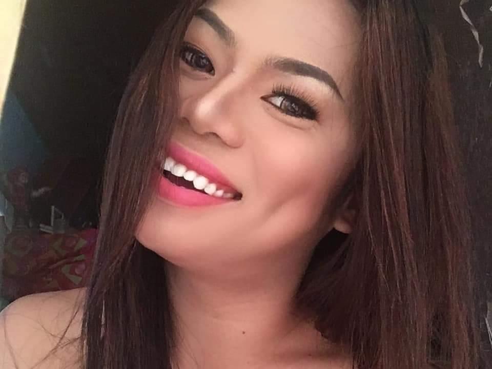 Hangadera has brown hair, thick eyebrows, pink lipstick, and a smiling face with white teeth, looking cute and sexy with a slight head tilt.