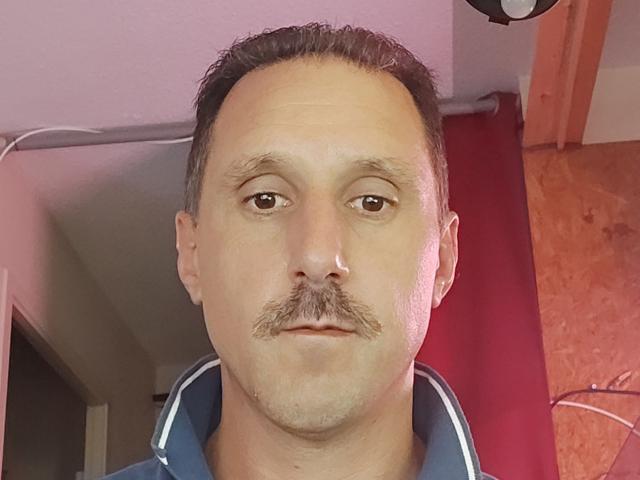 JefHotMan has a bald head, dark mustache, and is wearing a blue and white striped shirt in this selfie. His brown eyes are looking directly at the camera.