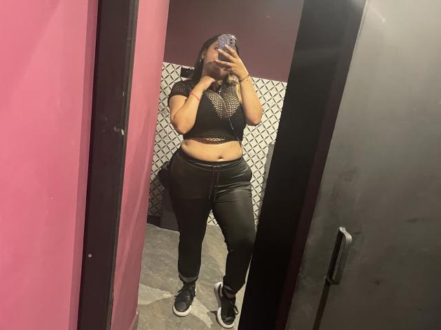 MissSofiia's mirror selfie shows her with dark skin, wearing a black mesh crop top, black leather pants, and sneakers, holding a phone covering her face.