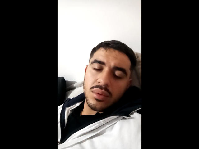 Elruglis69 has short dark hair, a beard, and closed eyes, wearing a black and white hoodie, looking sleepy and relaxed.