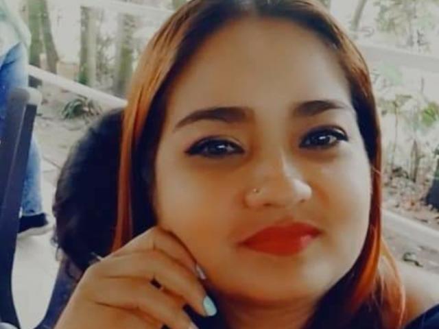 SoffiMilf has a chubby face with red lipstick, brown eyes, and orange-red hair, touching her cheek with a blue-nailbed hand. Her nose is pierced.