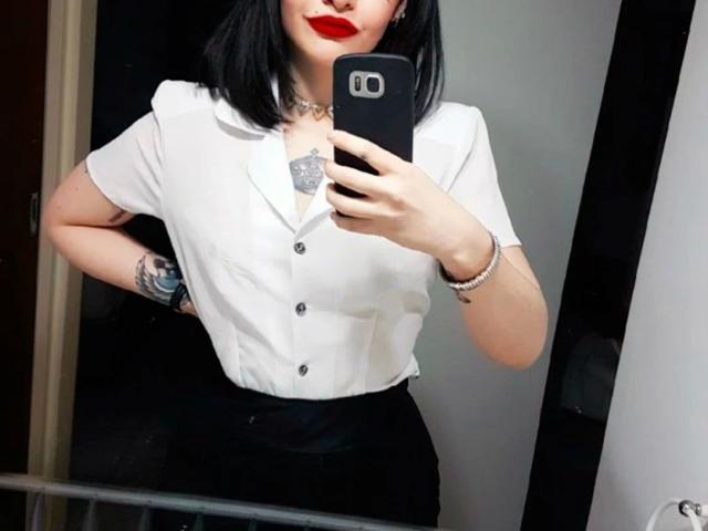 Celestia-hot with black bob, red lipstick, white button-up, black skirt, tattoo on chest, holding phone, showing ass, mirror selfie, bracelet, necklace, choker.