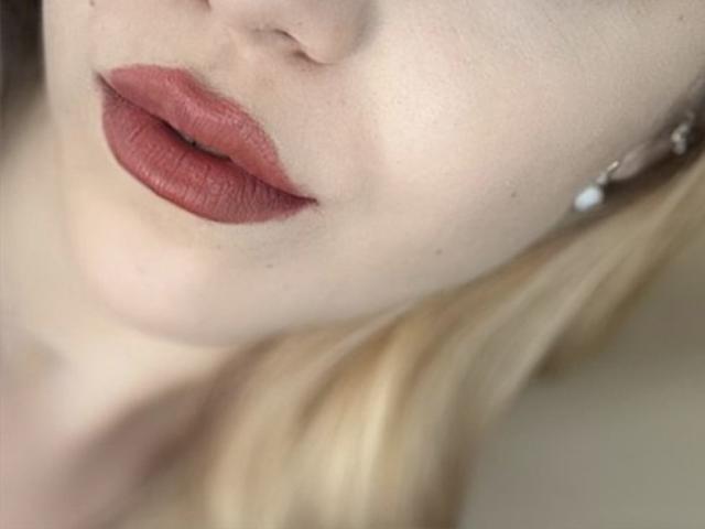 La piel pálida de SugarrX y su labial rojo mate, de textura opaca, son los elementos principales, con una ligera visión de su cabello rubio y un arete de plata en el lado derecho..