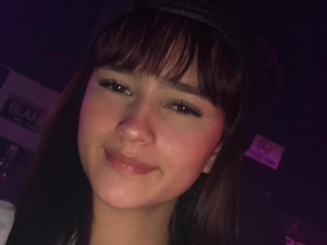 MelodyMansson has dark brown hair, bangs, and a slight smile. Her skin is fair with a pink blush, and she has long, dark eyelashes. She's wearing a black headband.