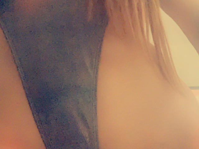 Icequren69's bare back with a gray thong, showing a deep side cutout and long brown hair falling down. Soft, warm lighting.