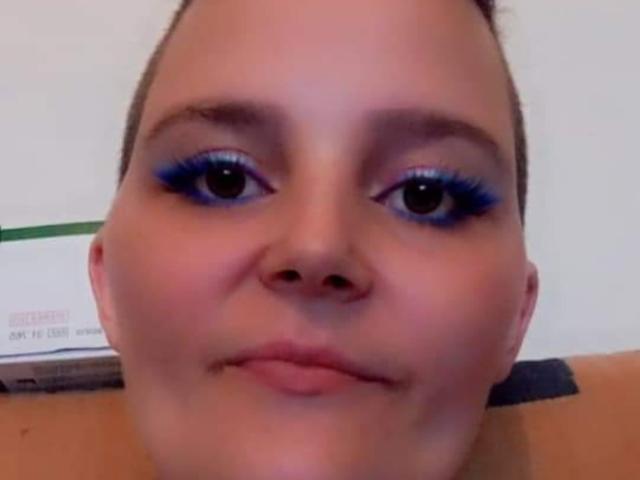Lya69x hat blaues Augen-Make-up, volle Augenbrauen und einen neutralen Gesichtsausdruck mit einem leichten Schmollmund. Ihre Haut ist glatt und sie schaut direkt in die Kamera..