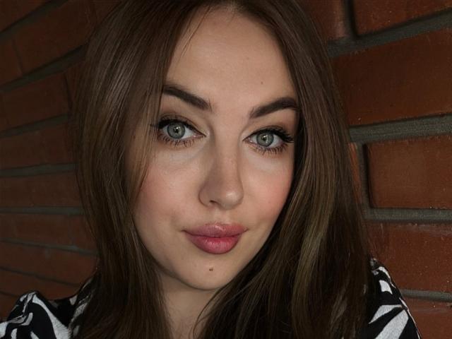 KaleyReed has blue eyes, full pink lips, and a small mole below her top lip. She's a cute brunette with straight hair and a black-and-white striped shirt.