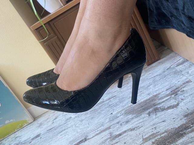 Mirellia's shiny black croc-sole high heels with stiletto heels are on her feet, showing off her pale skin and slightly visible veins.
