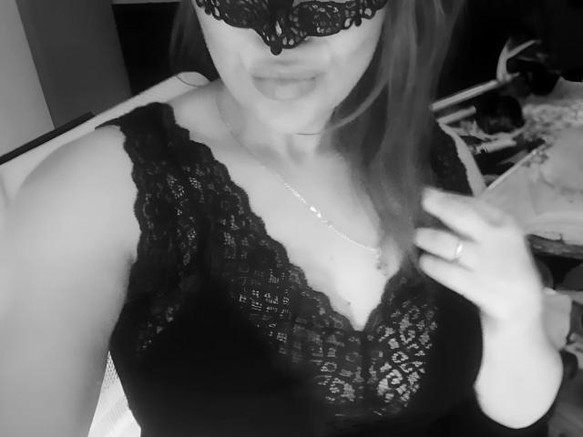SofiaBells with lace mask, black lace top, showing her tits, smiling, holding hair, ring on finger, necklace, and a ring. Black and white, sexy.
