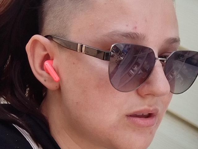 Alifil69 has a shaved side, wears reflective sunglasses, and has neon pink earbuds in. Skin is pale with a few small acne marks. Alifil69's lips are slightly parted.
