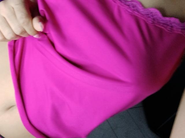 AnaisHilton's hand pulls up a bright pink shirt, revealing a bit of her flat, pale stomach. The shirt has lace trim on the side.