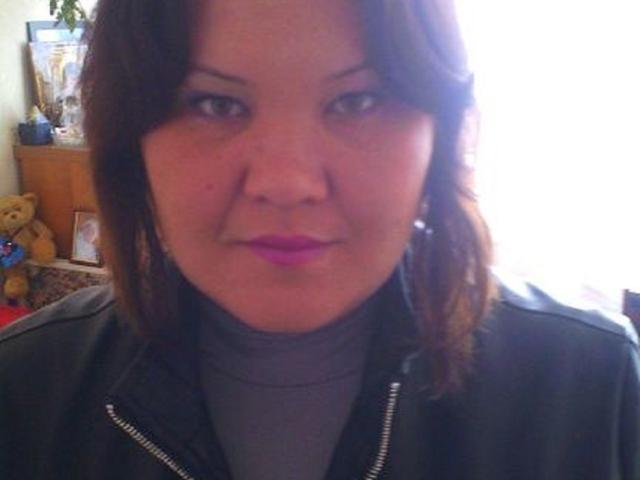 ElizabethFunny has medium brown hair, pink lipstick, and a slightly pouty face. She's wearing a black leather jacket over a gray turtleneck. Her tits are not visible.