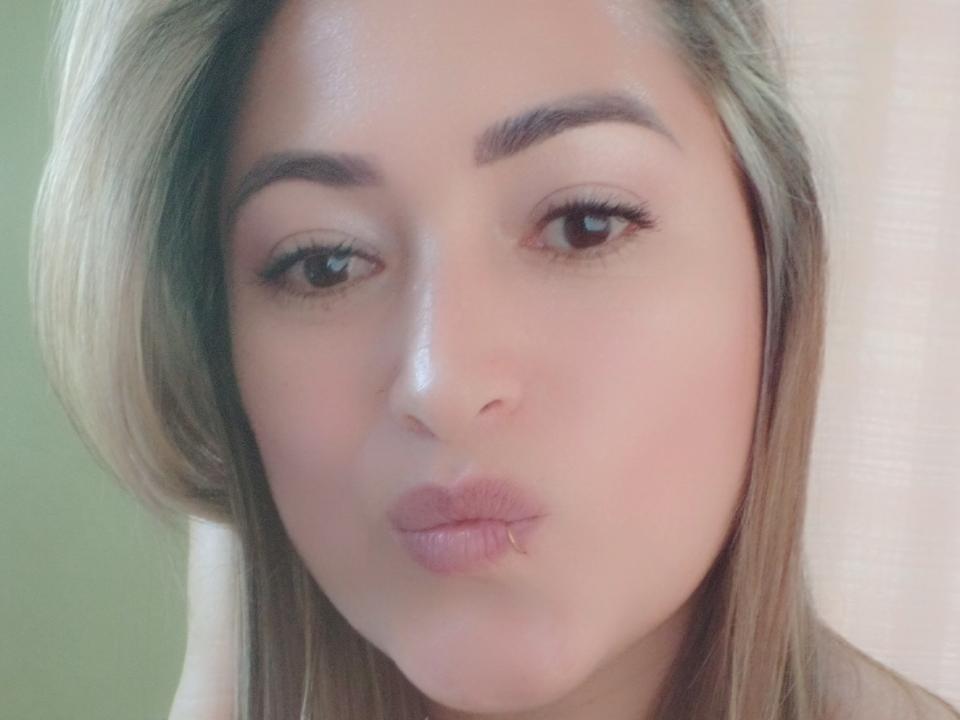 PrettyLoveCute has light brown skin, full pink lips puckered in a kiss, and slightly parted brown eyes. Blonde hair frames her face. She has well-groomed eyebrows and long lashes.