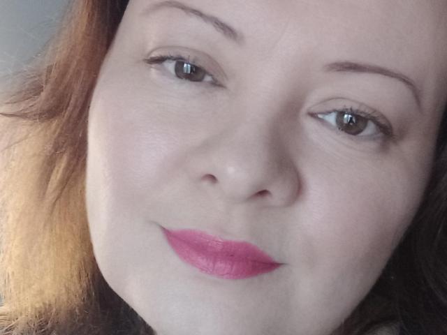 Il viso di MayDreamy ha la pelle chiara, gli occhi marroni e il rossetto rosa. Ha i capelli castani, le sopracciglia delicate e un leggero sorriso. Le sue ciglia sono visibili e sembra rilassata..