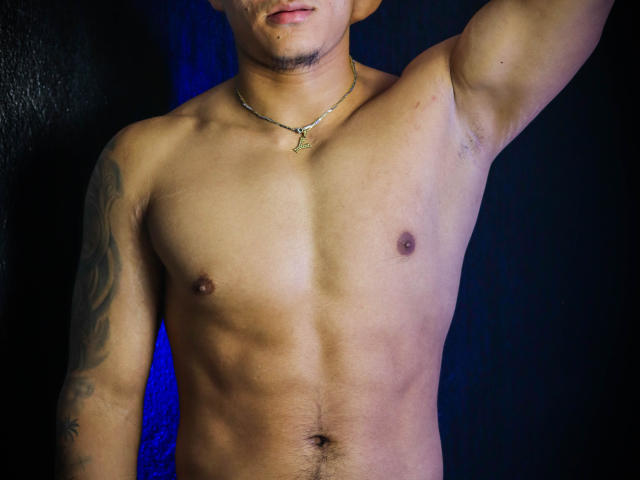 JeisonStark's shirtless torso, showing a smooth, muscular chest with small nipples and a tattoo on the right arm, wearing a necklace with a small pendant.