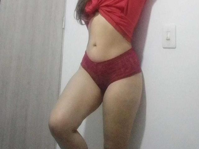 Los calzones rojos de SophieTeller, la camisa roja levantada, exponiendo su vientre plano y las marcas de bronceado. Sus piernas están ligeramente flexionadas, mostrando sus muslos gruesos y piel desnuda..
