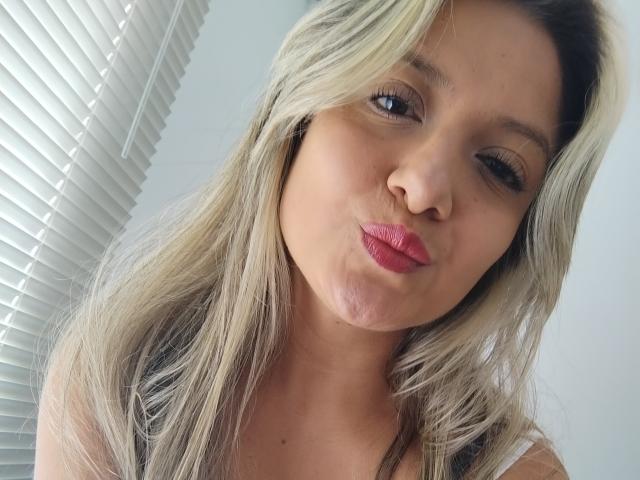 ValeriaHunter69 with blonde hair, pouty pink lips, and winking right eye, showing off her cute face in a selfie. She's got a sexy, slightly mischievous look.
