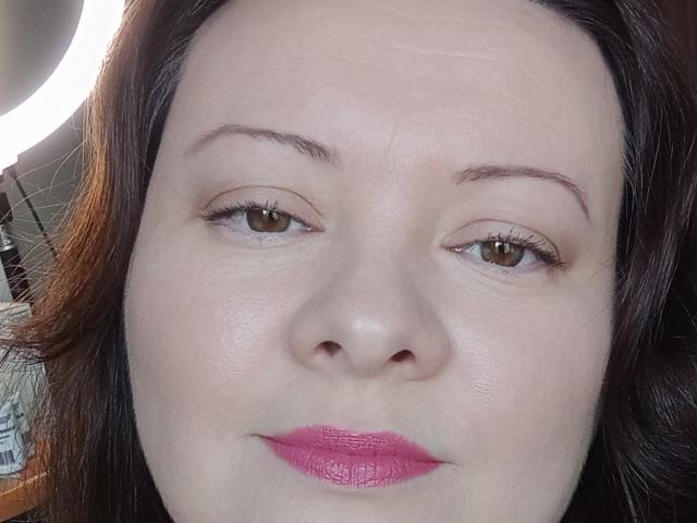 MayDreamy's face, showing fair skin, brown eyes, pink lipstick, subtle makeup, and dark brown hair. Her nose is centered, and she's looking slightly to the right.