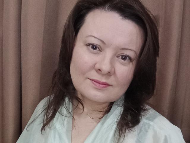 MayDreamy has light skin, brown eyes, and medium-length dark brown hair. She's wearing a greenish-tinged shirt with a subtle pattern, and has a slight, pink-lipsticked smile.