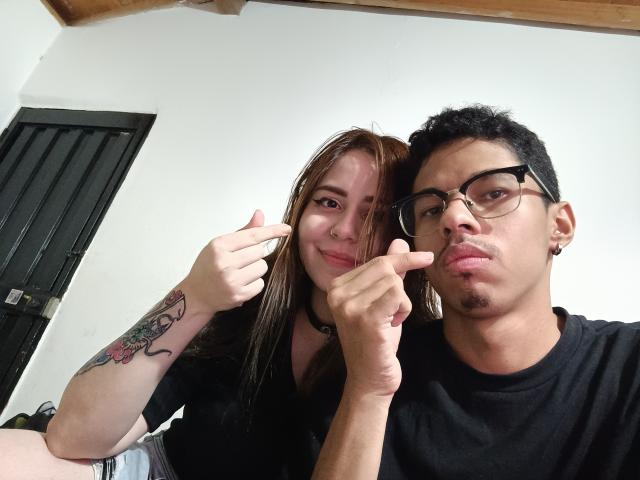 JadenAndFairyMelanie, a cute girl with a tattoo on her arm and a black shirt, and a guy with glasses and a black shirt, giving a thumbs-up and pointing.