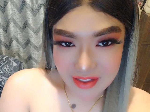DevilishMind: Una donna dalla pelle chiara, con rossetto rosso e eyeliner marcato, che mette in mostra il seno e le labbra piene, indossa una collana d'oro e ha lunghi capelli biondi, lisci..