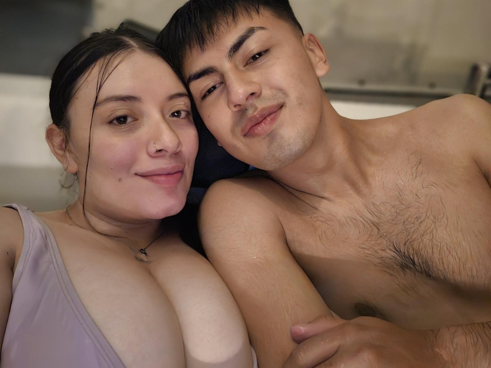 FaniNdGreg and FaniNdGreg, both shirtless, with FaniNdGreg's boobs pressed against FaniNdGreg's hairy chest. FaniNdGreg has dark hair, a slight smile, and a nose ring. FaniNdGreg's pink tank top.