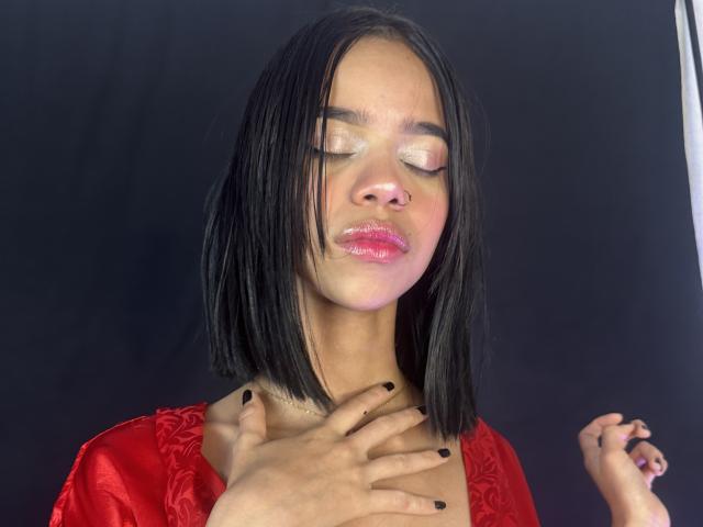 LiaBlom with shiny pink eyes, black straight bob, glossy pink lips, red dress, black nails, hand on chest, dark background. Boobless, no ass, no pussy. Pretty, sexy.