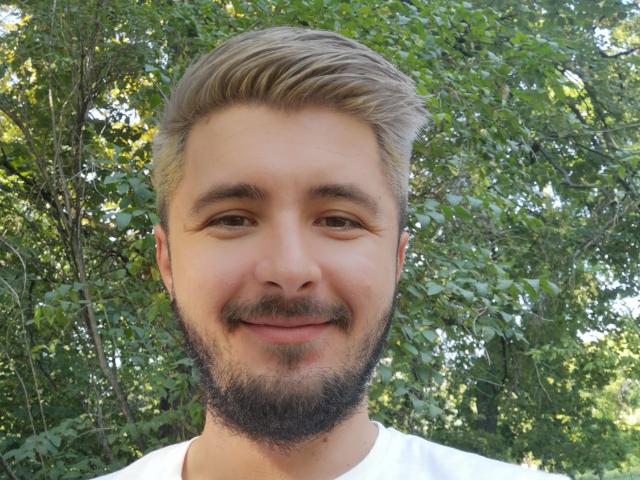 ChanceOfGod has a light brown beard, short blond hair, and a white shirt. His face is smiling with a slightly chubby nose and small brown eyes.