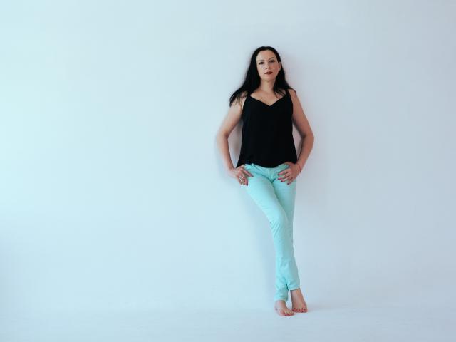 ElizabethSo, barefoot, wearing black top, light blue jeans, standing with hands on hips, long black hair, white background, smiling, straight posture, slim, small tits, cute.