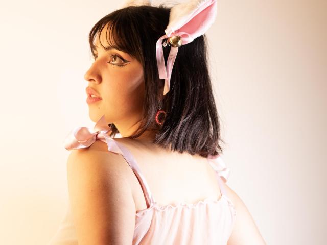 VickyButerfly with pink bunny ears, pink ribbons, and a pink dress, facing sideways, showing her profile with a slight smile, and a cute red earring.