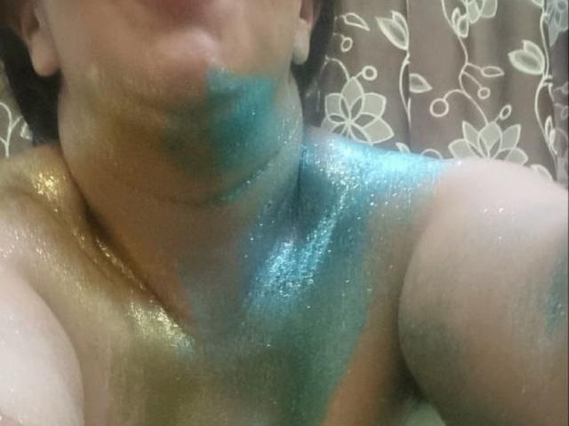 CatalinaJH's upper body with glittery blue and gold paint on neck and chest, partially visible face, and short brown hair, in a slightly blurry selfie.