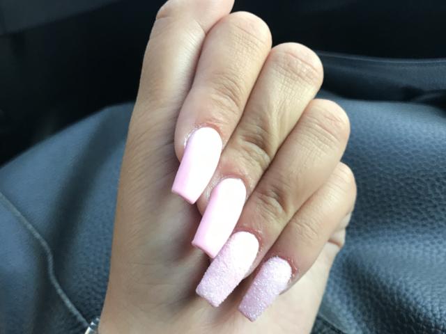 AlexaLip's hand with pink and white textured, square-tipped nails, showing off a cute, pastel manicure on her fingers. Her skin is light, and she's wearing a black leather seat.