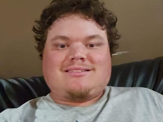 Dillondiape69 hat lockiges, braunes Haar, einen leichten Schnurrbart und lächelt mit rosafarbenen Wangen. Auf dem Selfie trägt er ein graues Hemd..